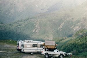 A car and camper van set up camp in a serene mountainous landscape, perfect for an adventurous escape.